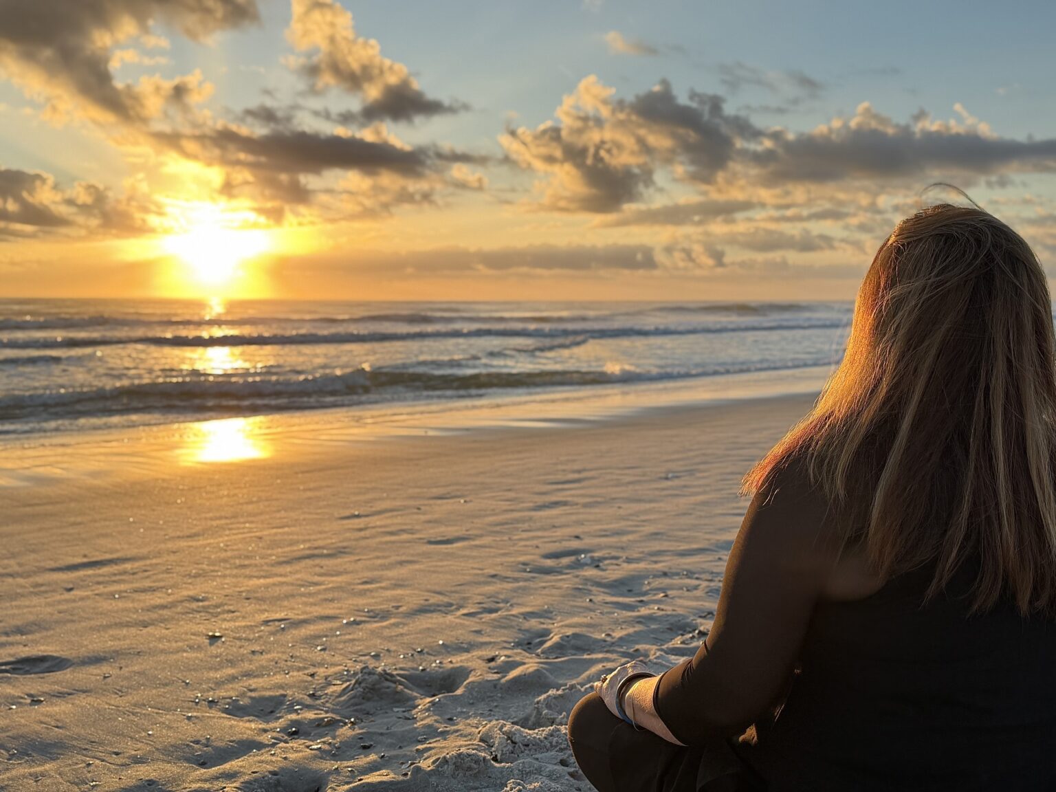Person watching a golden sunset over a calm beach.